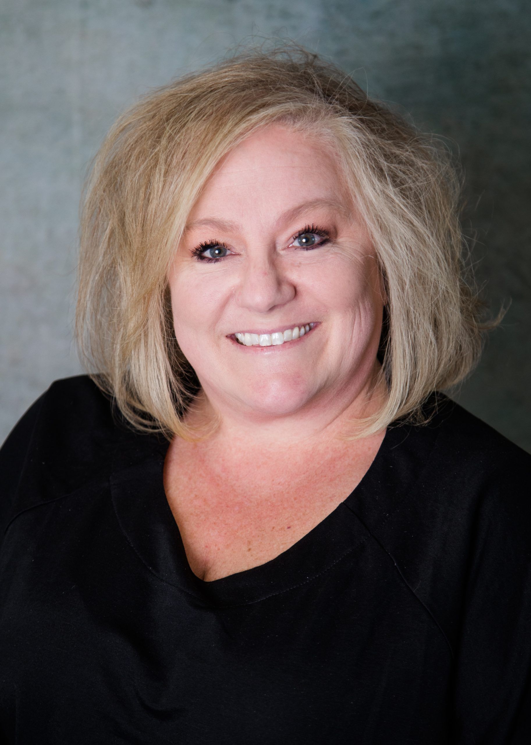 A woman in a black shirt is smiling for the camera.