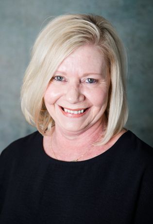 A woman with blonde hair is smiling and wearing a black shirt.