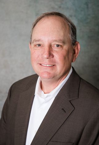 A man in a suit and white shirt is smiling for the camera.