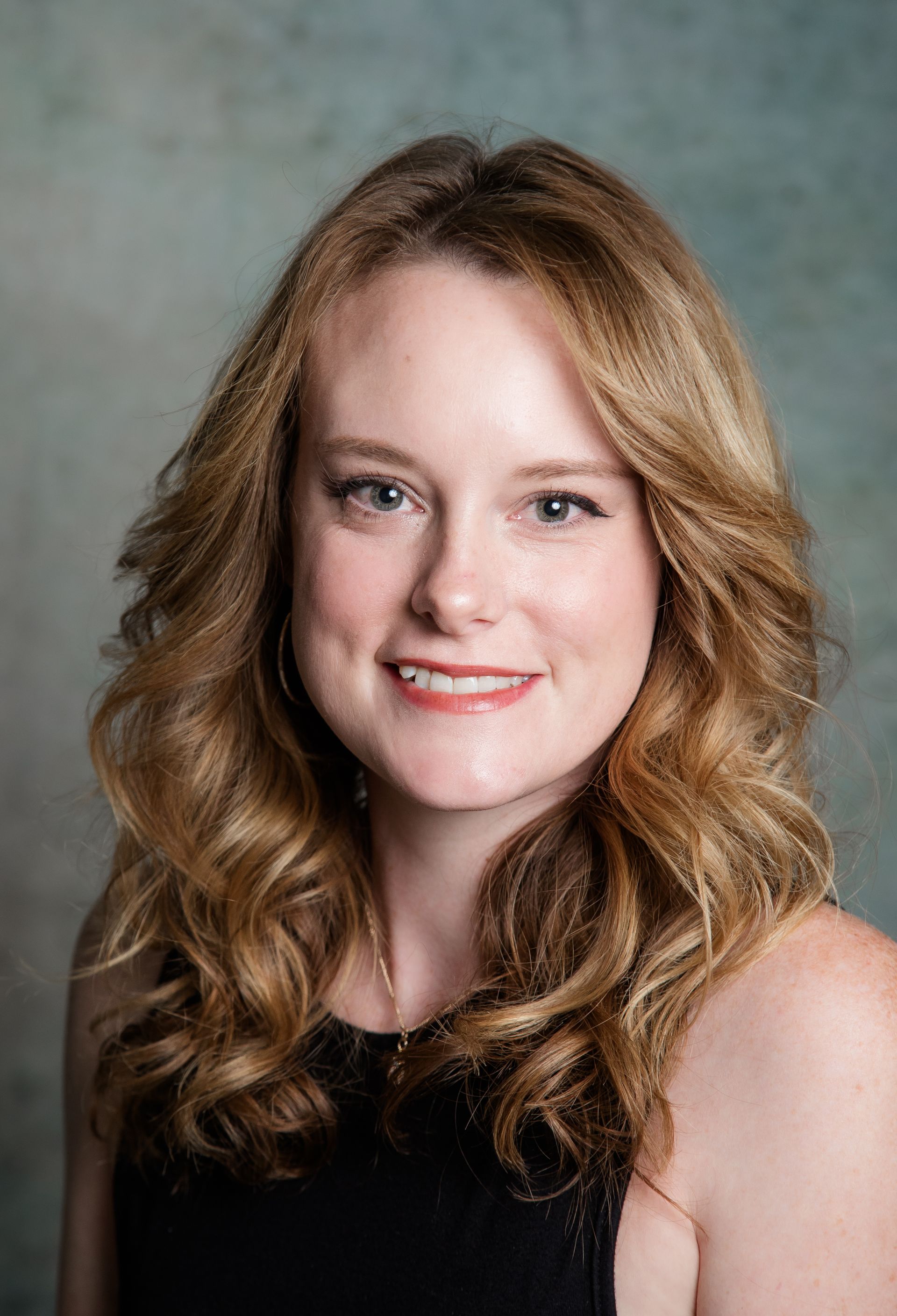 The woman is wearing a black shirt and smiling for the camera.
