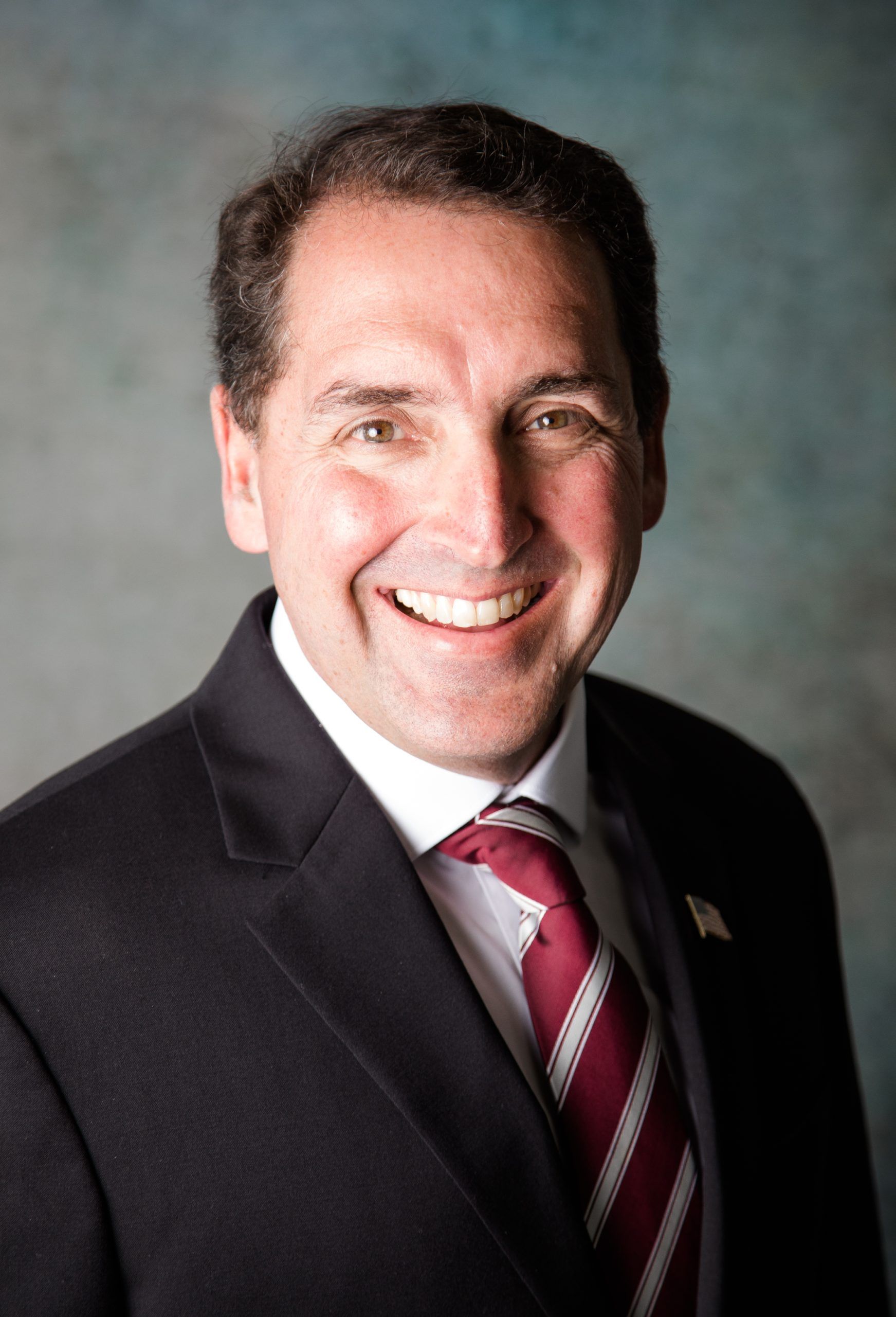 A man in a suit and tie is smiling for the camera