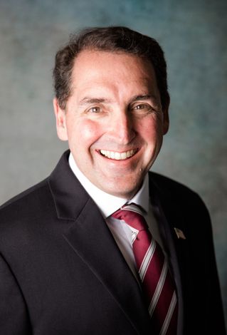 A man in a suit and tie is smiling for the camera