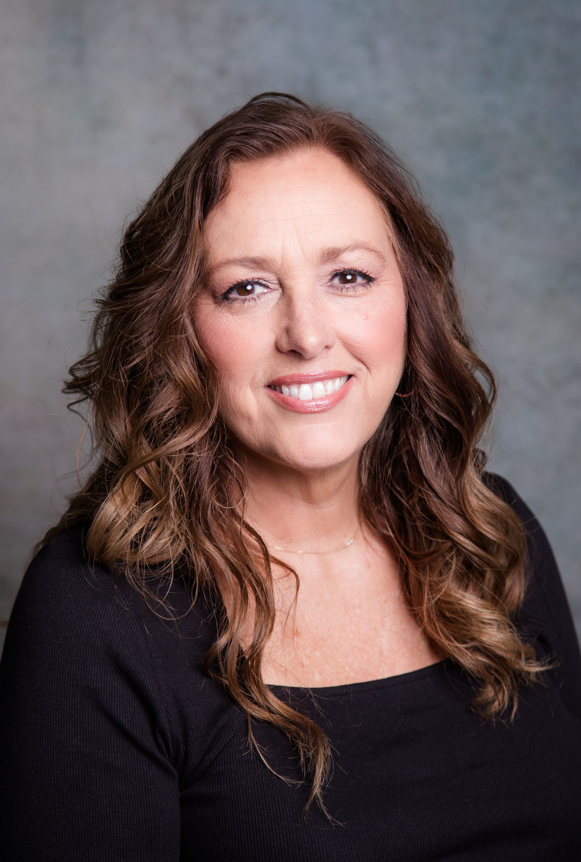 A woman in a black sweater is smiling for the camera.