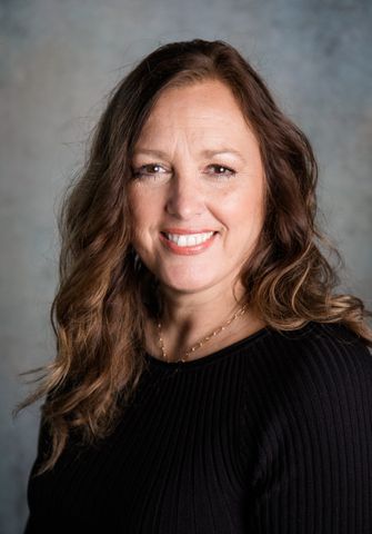 A woman in a black sweater is smiling for the camera.