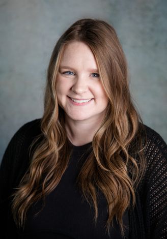 The woman is wearing a black sweater and smiling for the camera.