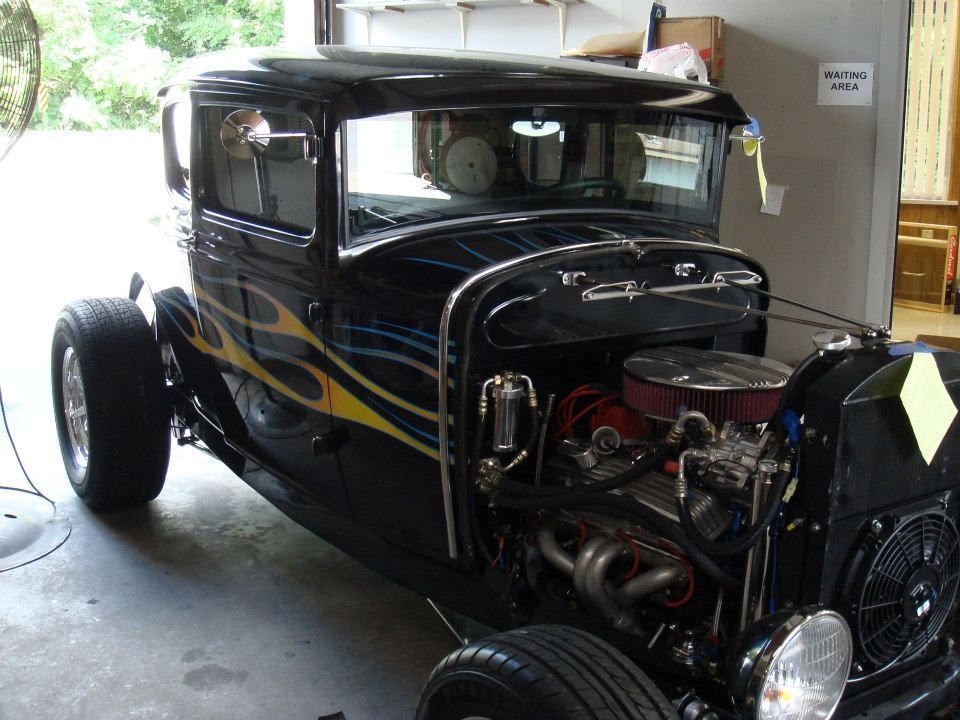 A black car with flames painted on it is parked in a garage