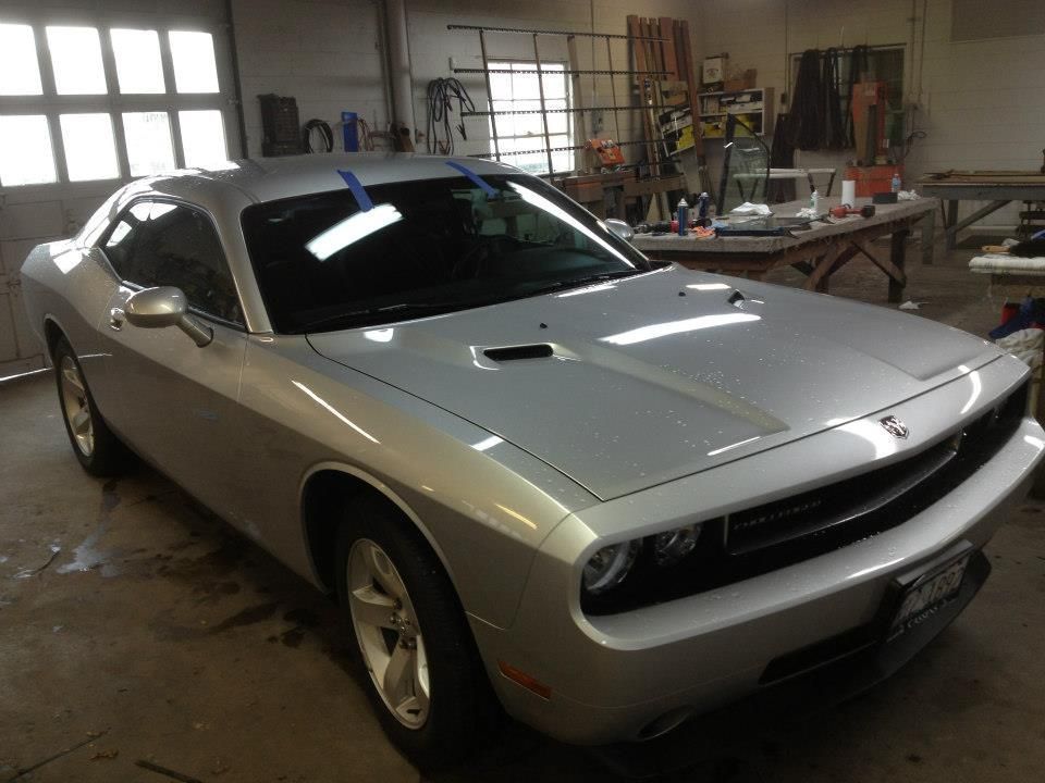 A silver dodge challenger is parked in a garage