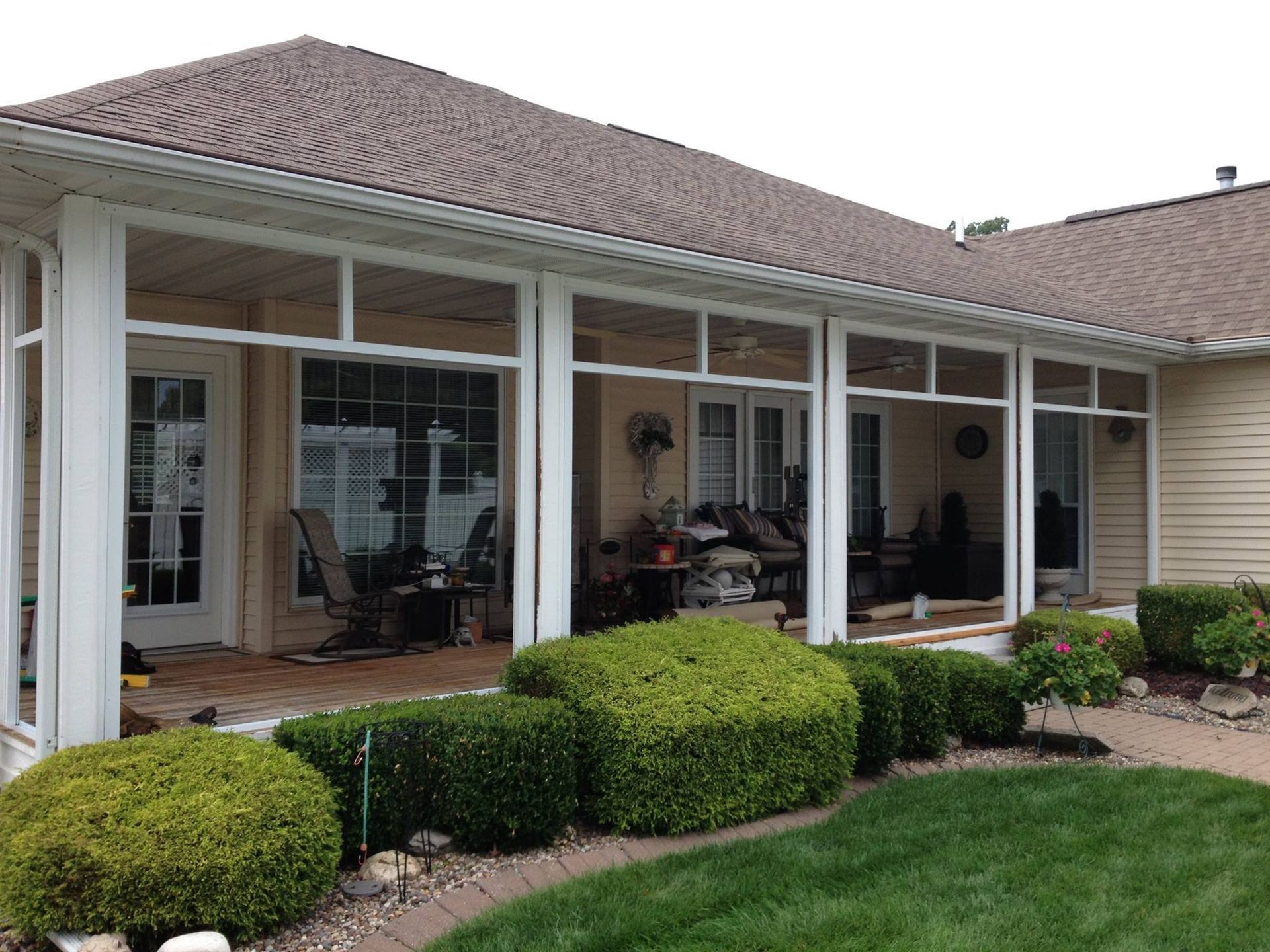 A house with a screened in porch and a lawn in front of it.