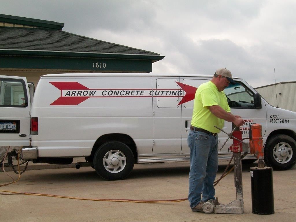 Man using concrete saw next to a white van with 
