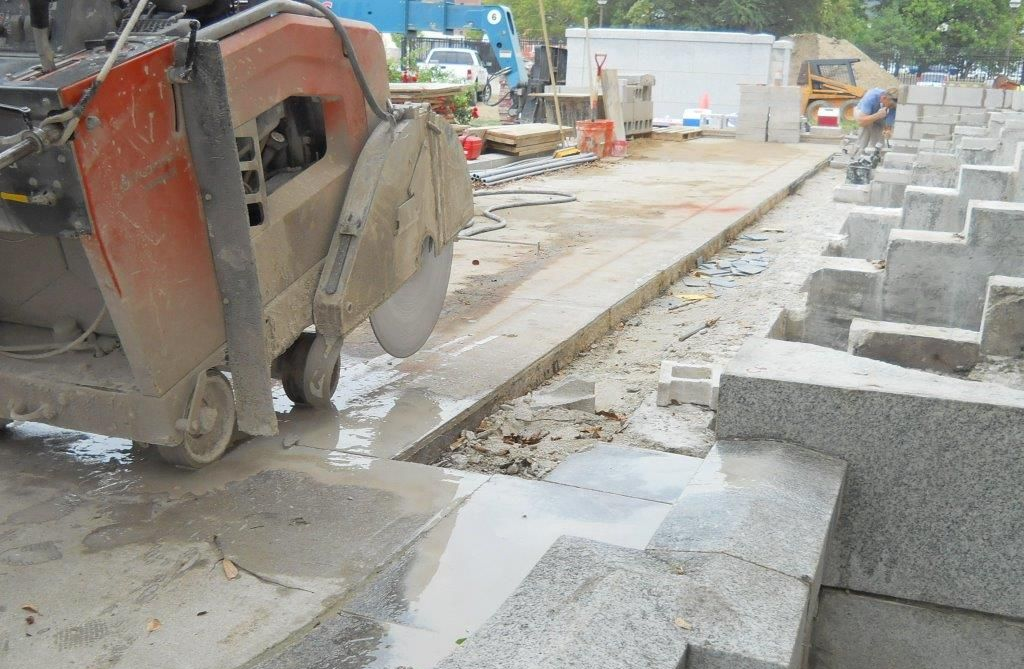 Concrete saw cutting a path through granite steps, construction site.