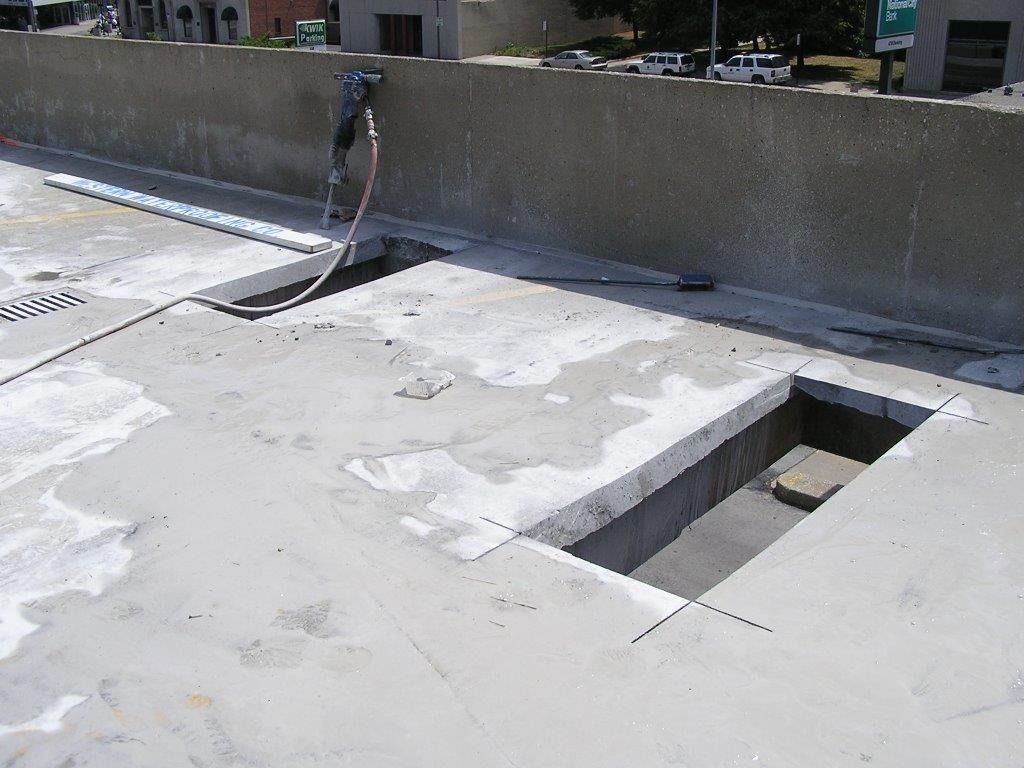 Concrete surface with two rectangular openings, construction site, worker using tools.