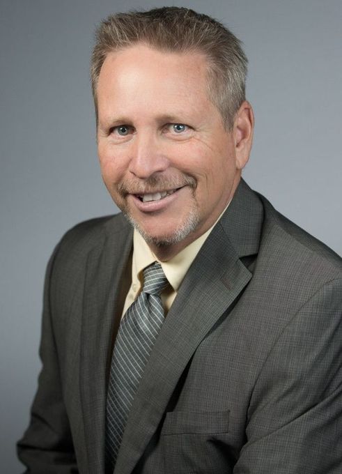 A man in a suit and tie is smiling for the camera.