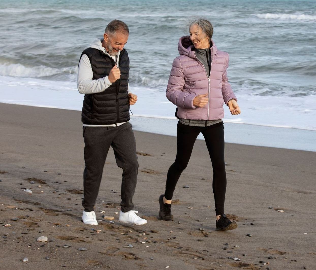 A man and a woman are walking on the beach.