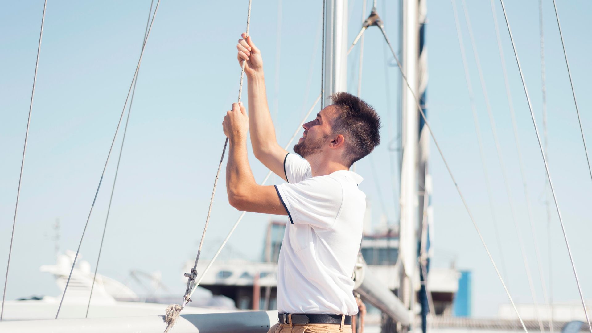 A man is working on the sails of a sailboat.