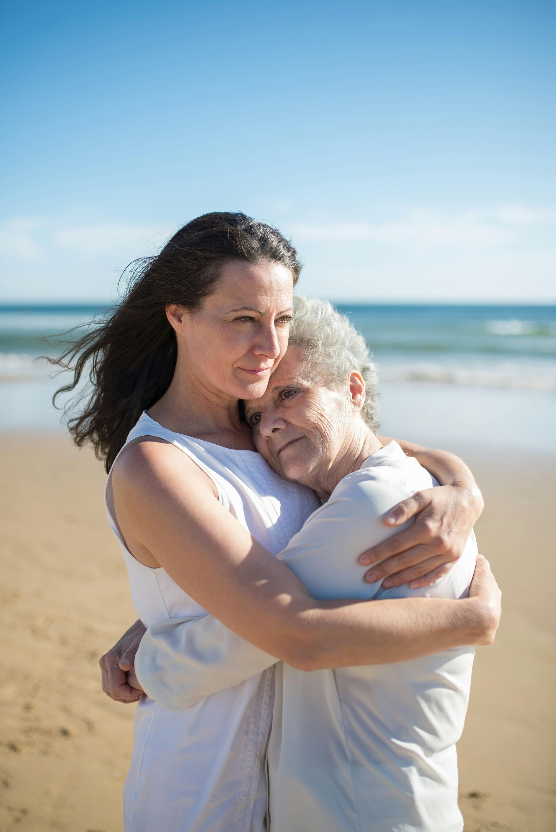 A woman is hugging an older woman on the beach.