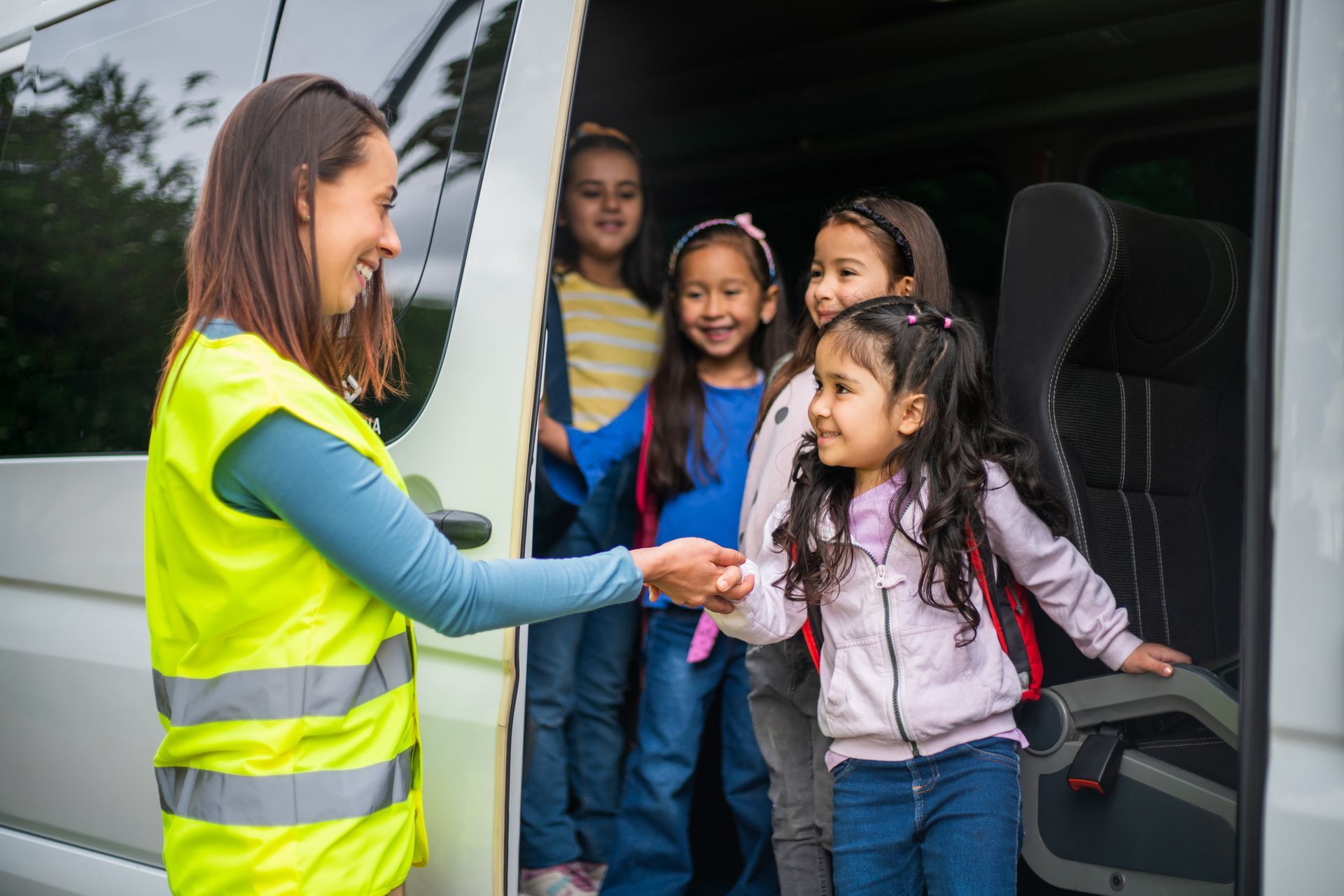 Bus driver helping a group of children get off the school bus.