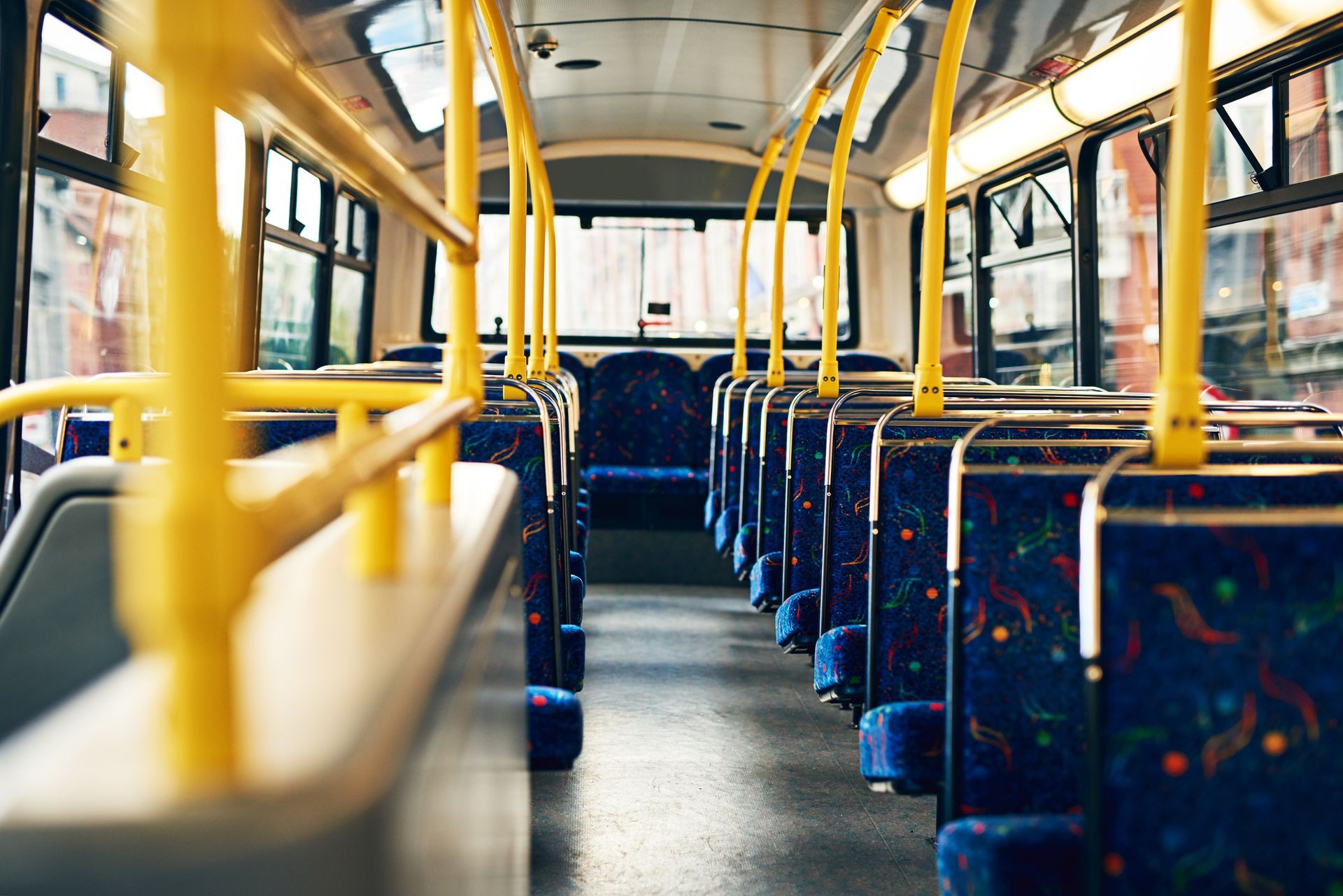 Empty double-decker bus interior with yellow rails and blue seats.