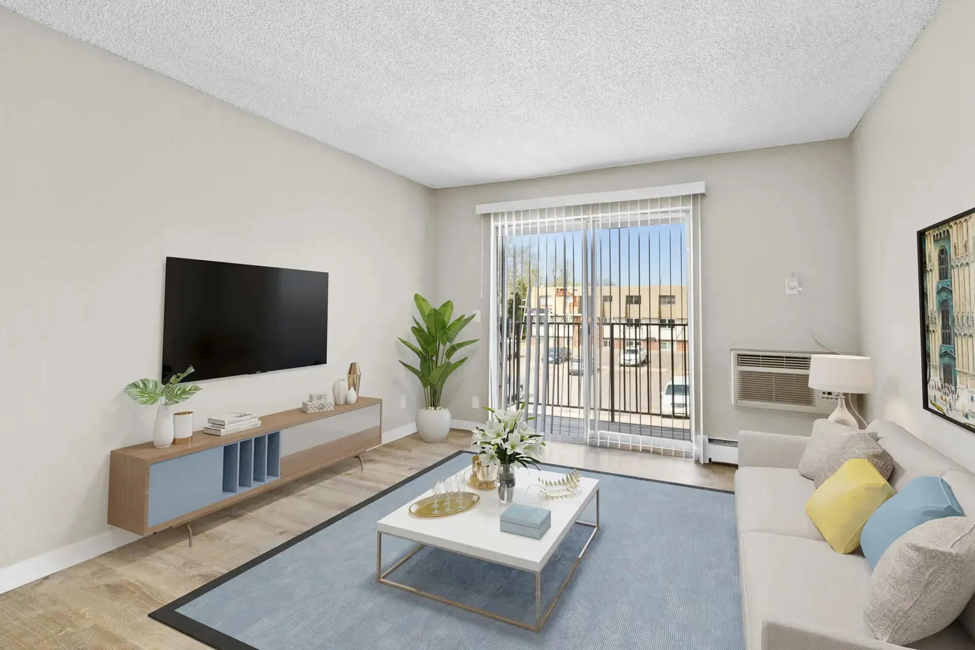Living room in an apartment with a wall-mounted TV, sofa, coffee table, and sliding door to a balcony.