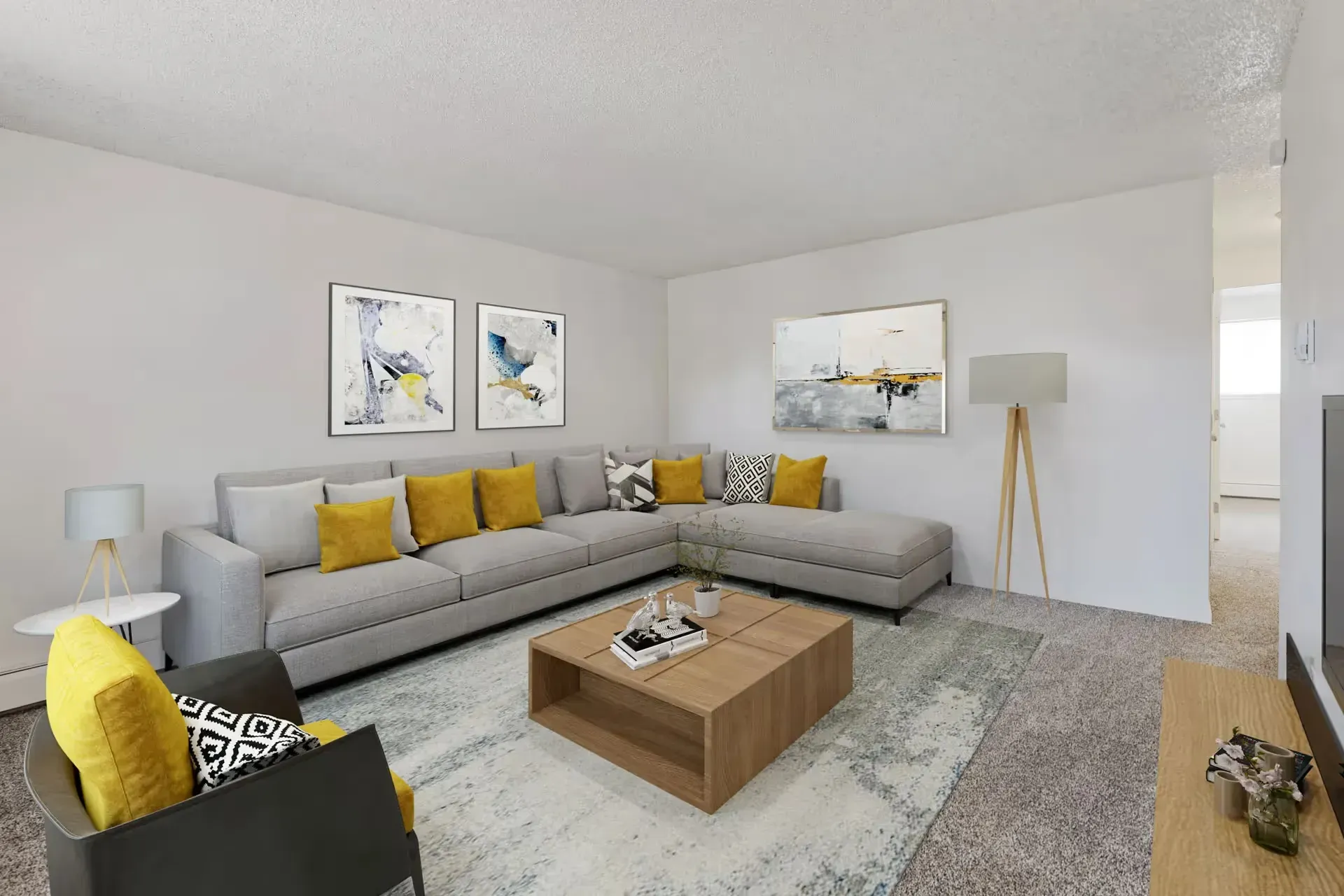 Modern living room in an apartment with a gray sectional sofa, yellow throw pillows, and abstract art.