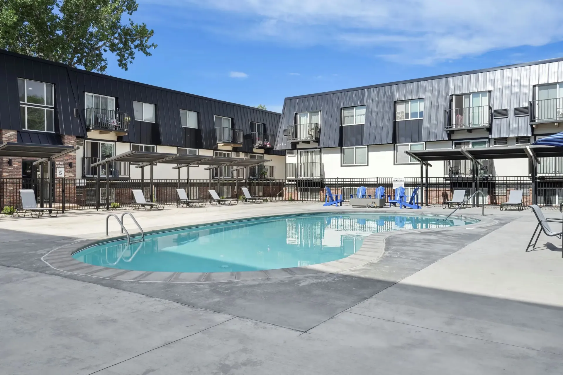 Outdoor pool area with lounge chairs and a modern apartment building in the background.