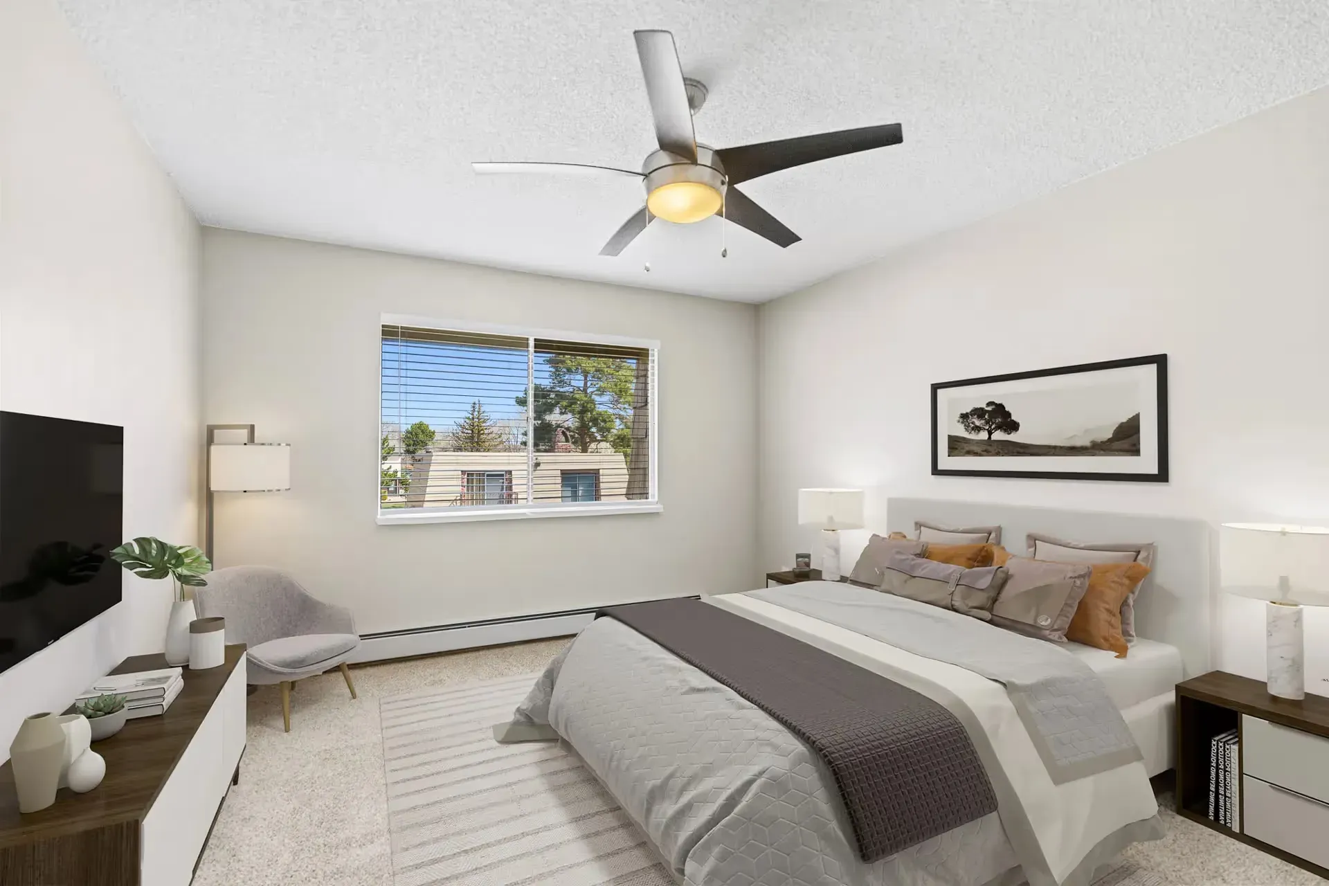 Bedroom in a modern apartment with a bed, two nightstands, lamps, ceiling fan, and a window.