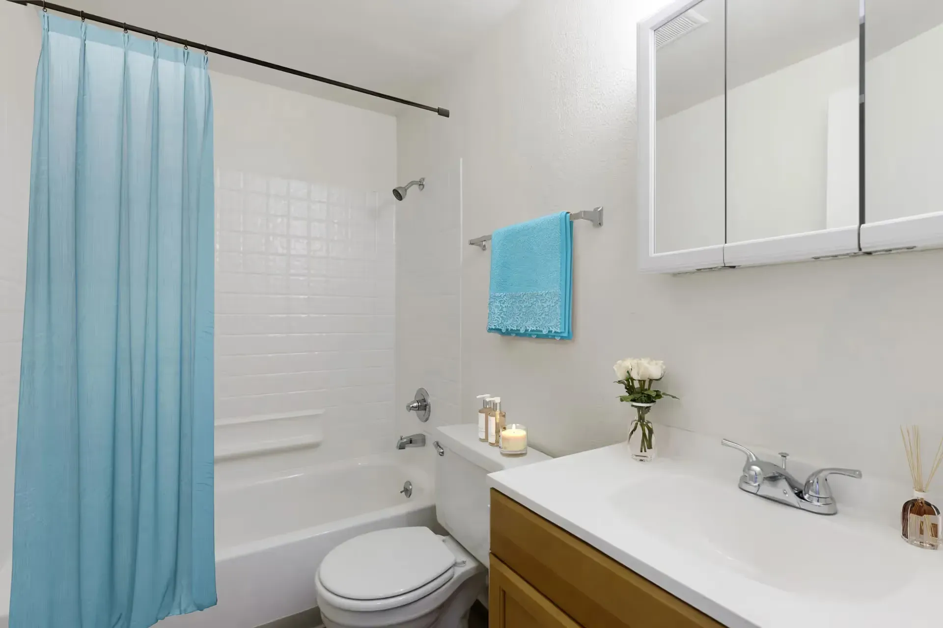 Bathroom in an apartment with a blue shower curtain, white tub, and vanity.