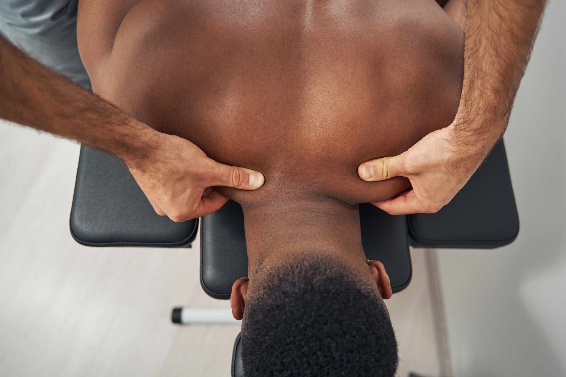 Hands pressing a person's upper back during a massage on a treatment table