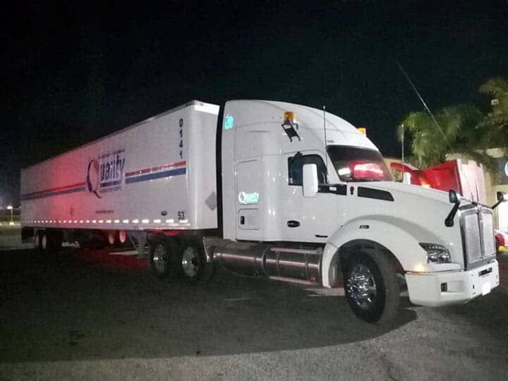 Un camión blanco está estacionado en un estacionamiento por la noche