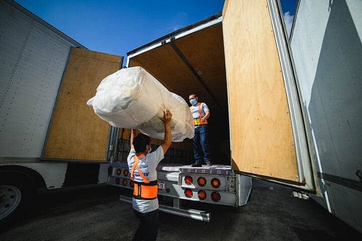 Un hombre carga un colchón en un camión.