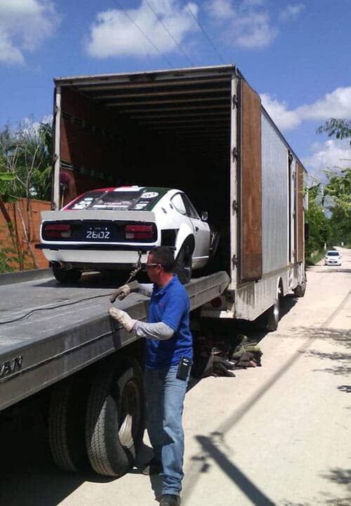 Un hombre con una camisa azul está cargando un coche en un camión