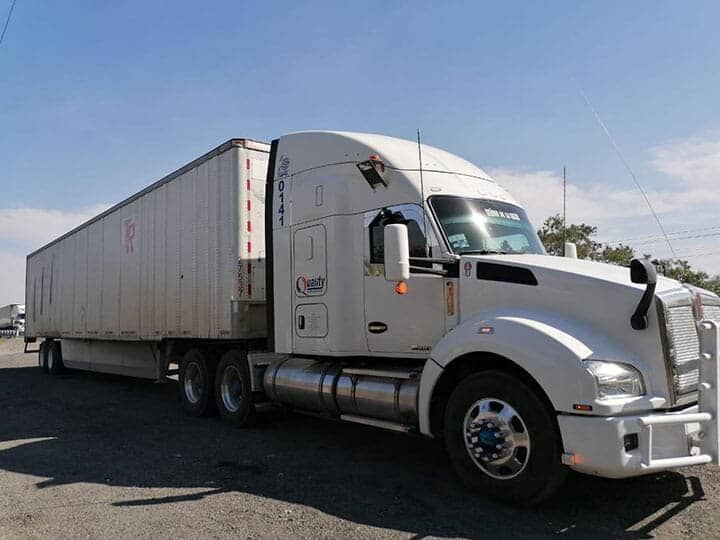 Un camión blanco está estacionado junto a un remolque blanco.