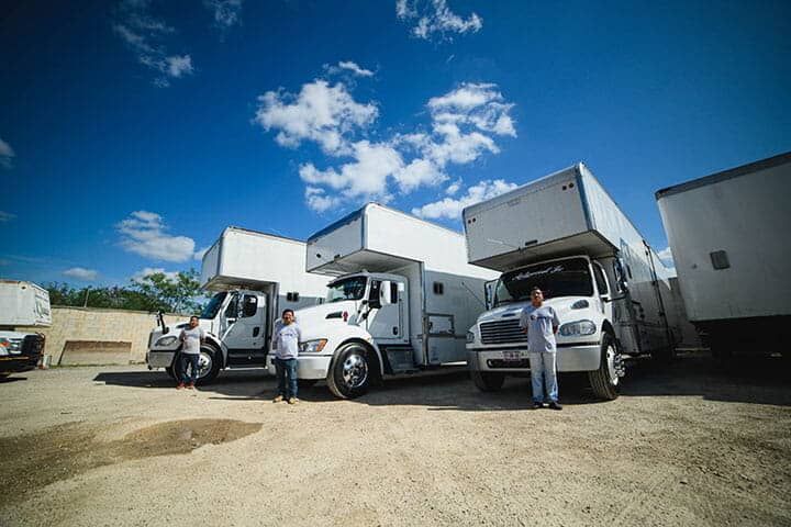 Un hombre y una mujer están parados frente a una fila de camiones en movimiento.