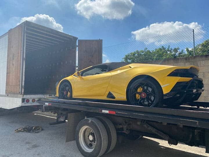 Un coche deportivo amarillo está siendo remolcado por una grúa.