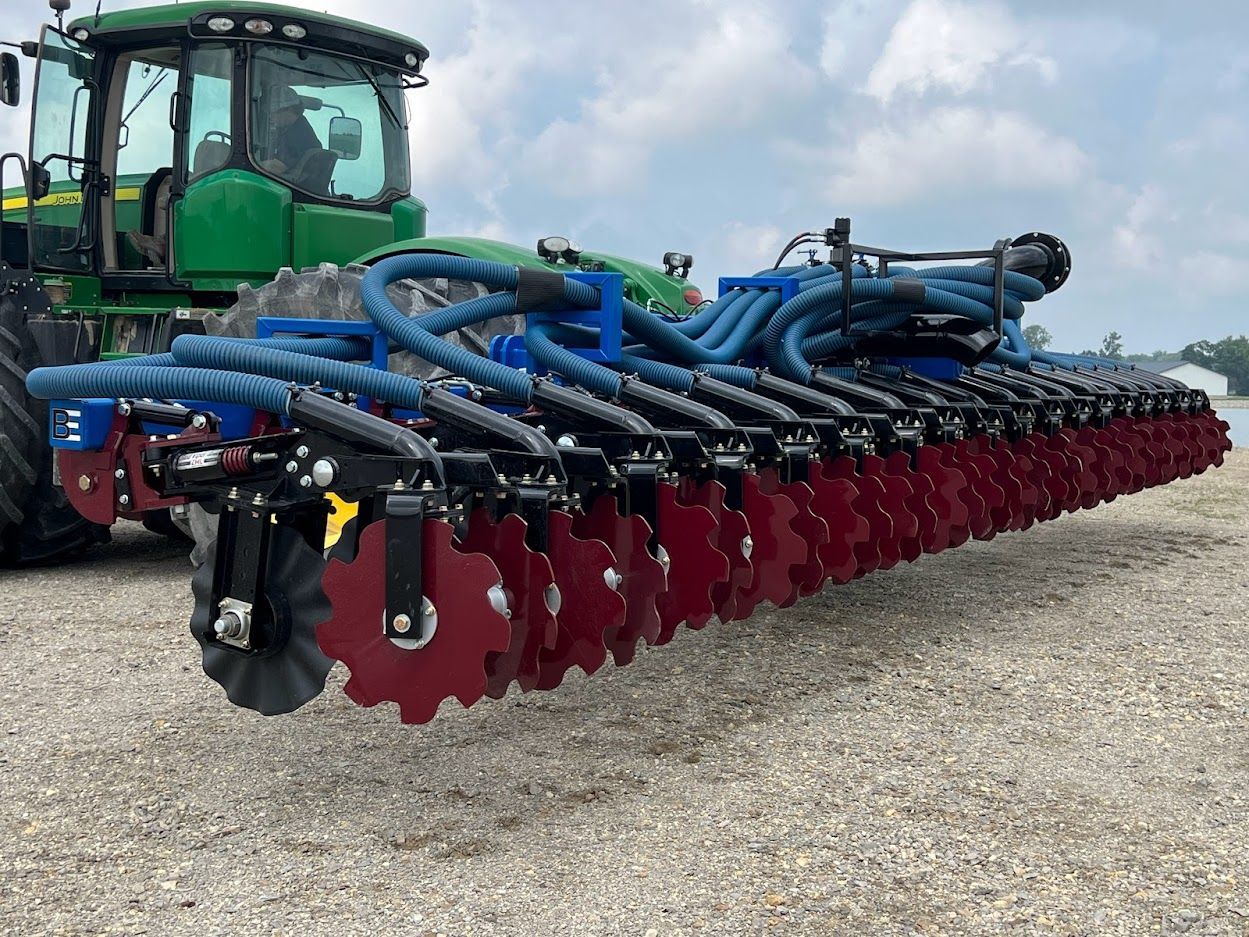A green tractor is parked next to a blue and red tractor.
