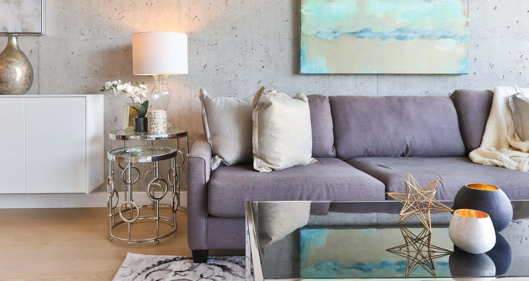 A living room with a purple couch and a glass coffee table