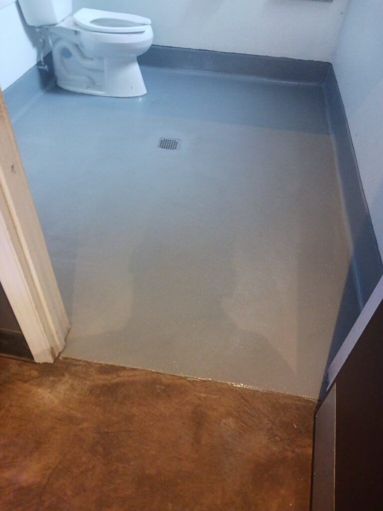 A toilet is sitting on a gray floor in a bathroom — San Leandro, CA — Mission Flooring and Countertop Design