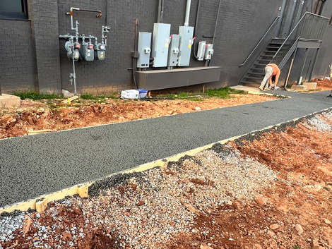 A man is working on a sidewalk in front of a building.