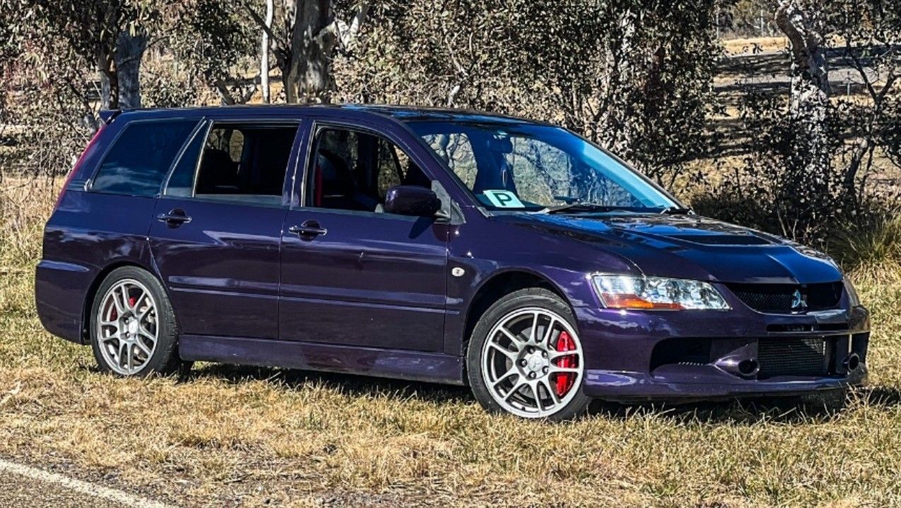 Purple Mitsubishi Lancer Evolution wagon on grass, red brake calipers visible. — Moto Bodyworks in Fyshwick, ACT