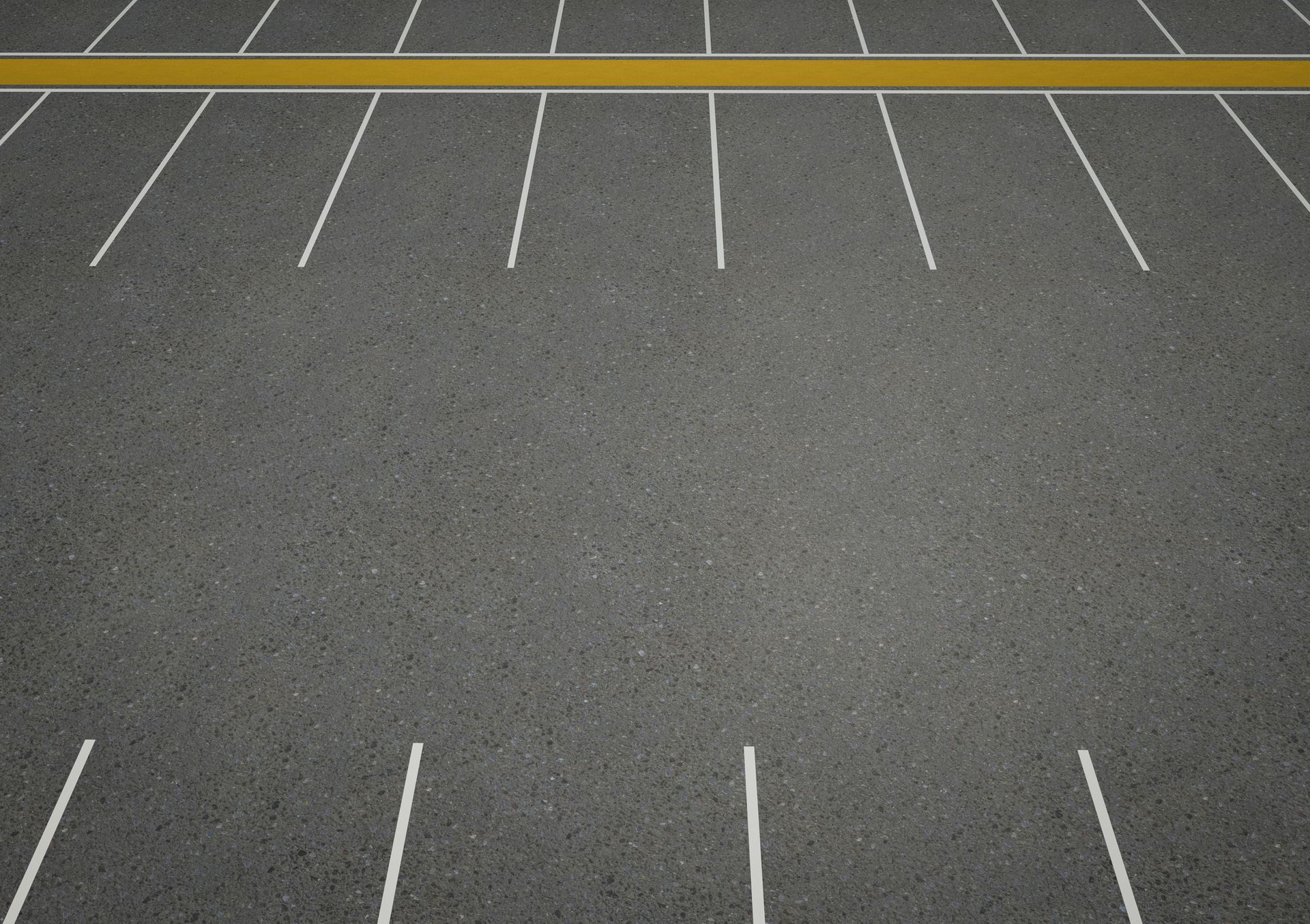 Empty asphalt parking lot with white parking space lines and a yellow center line.