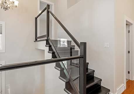 Staircase with a glass railing and a black banister 
