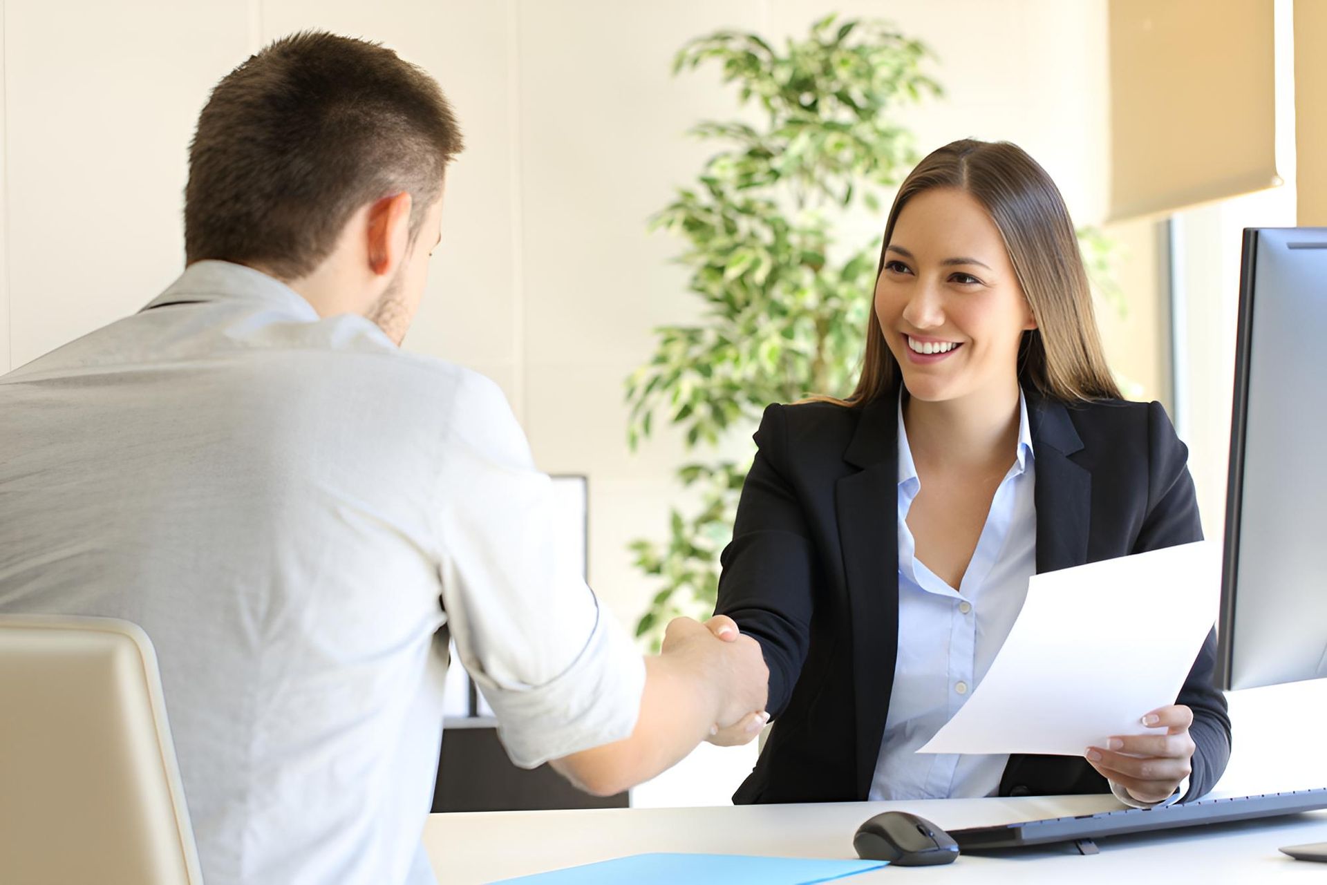 A woman is shaking hands with a man during a job interview — Bee HR in Newcastle, NSW