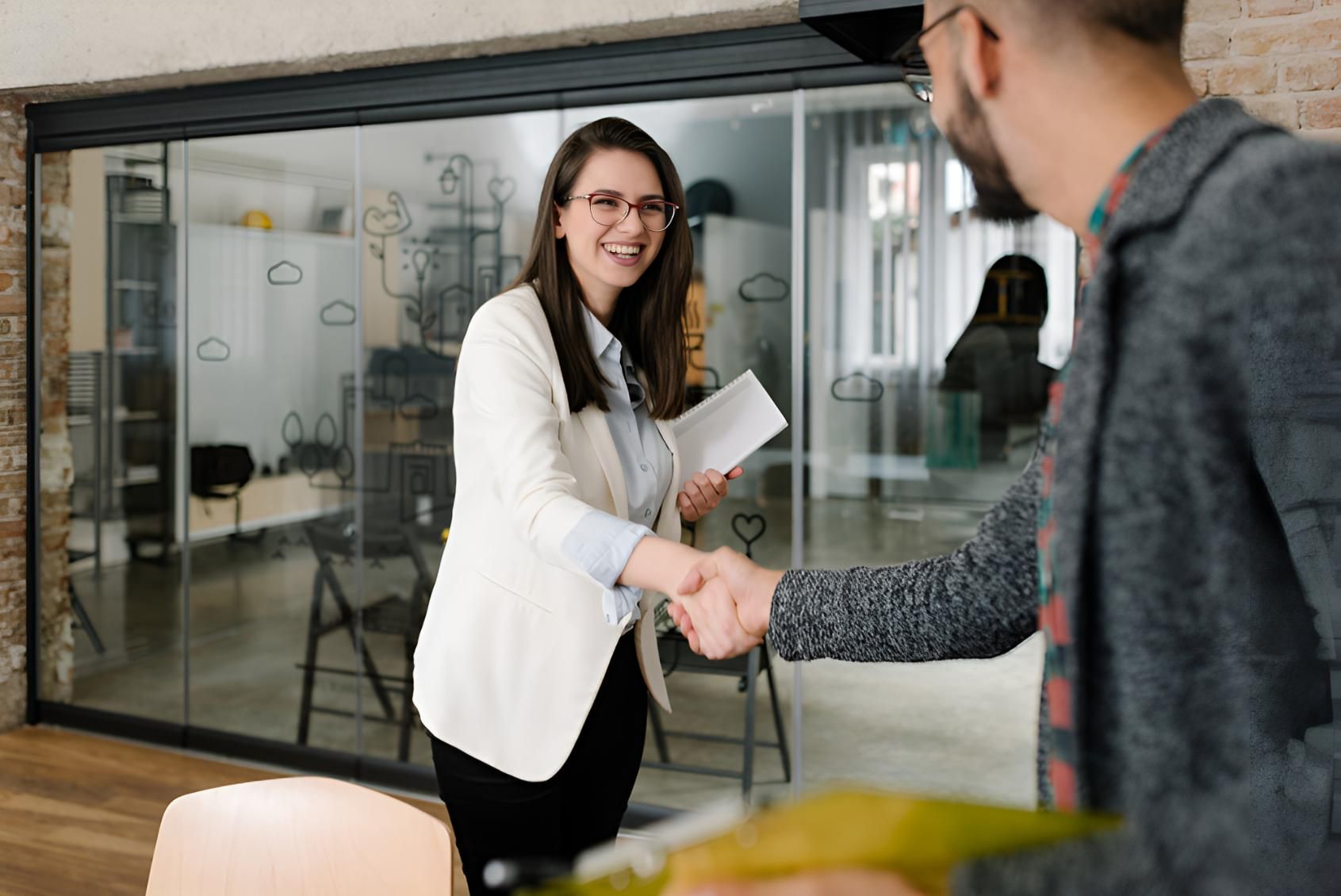 Woman is Shaking Hands With a Man in an Office — Bee HR in Newcastle, NSW