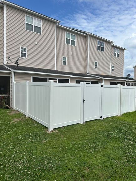 A white fence is in front of a row of houses.