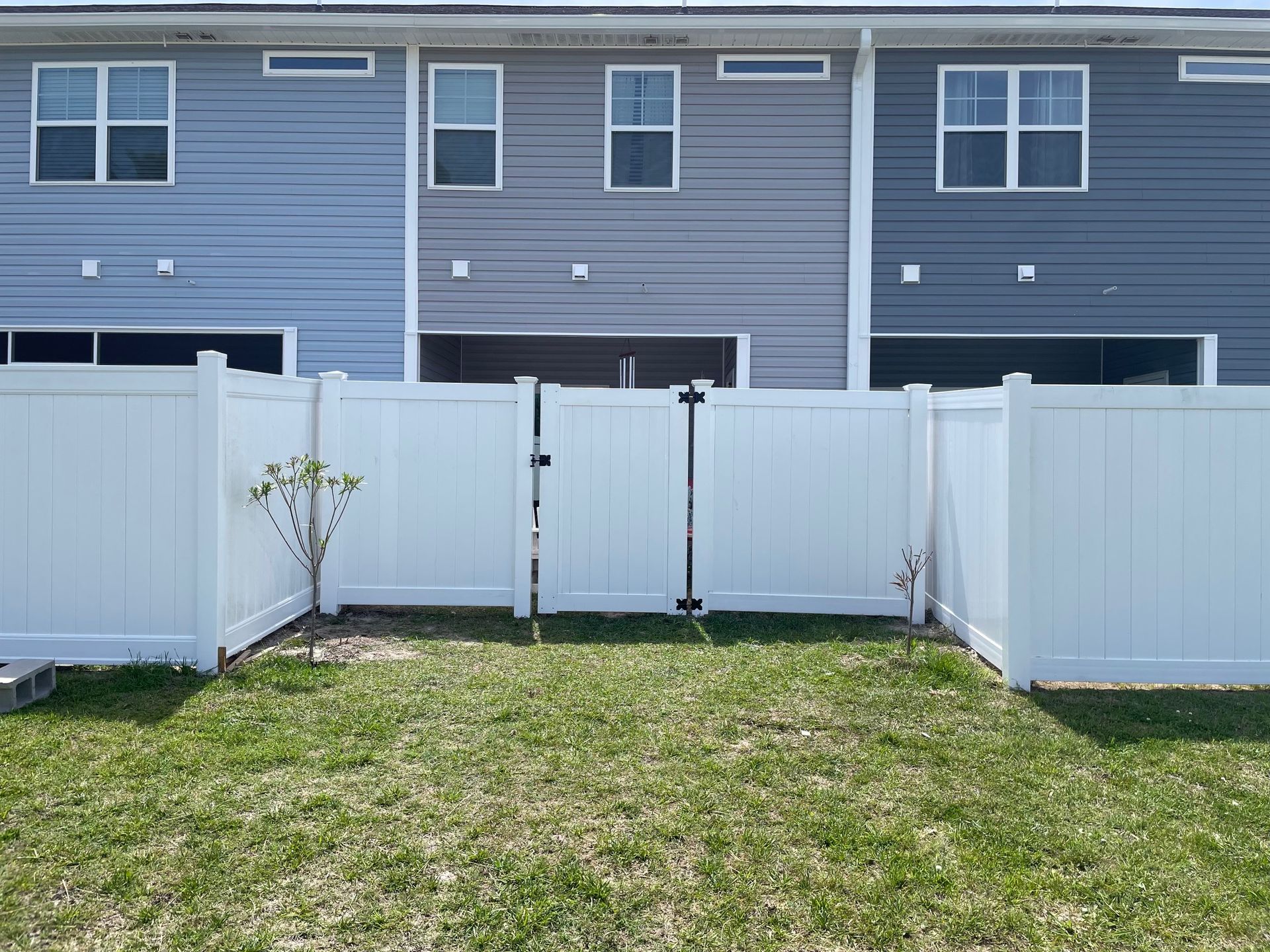 There is a white fence in the backyard of a house.