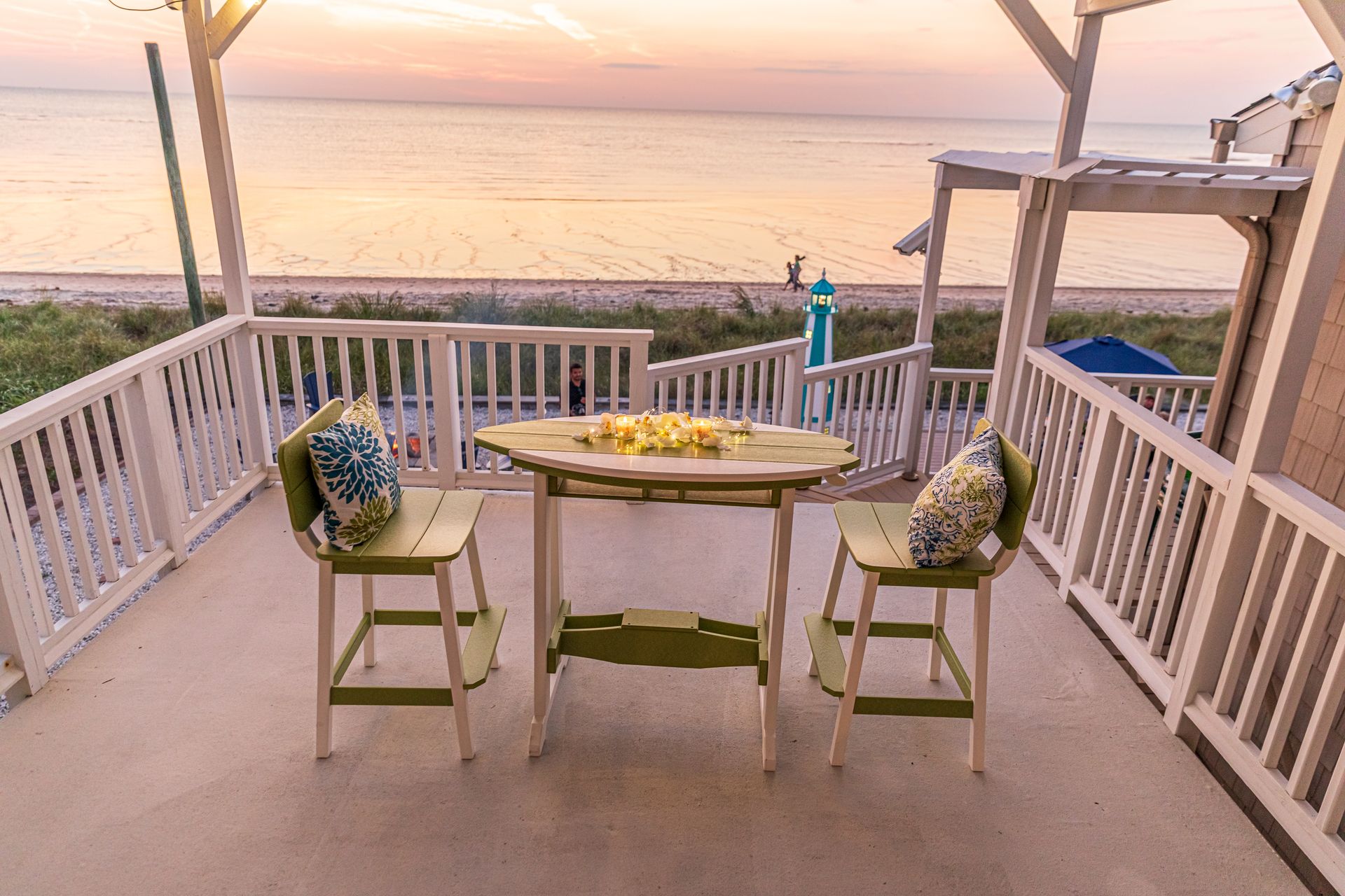 A table and chairs on a porch overlooking the ocean.