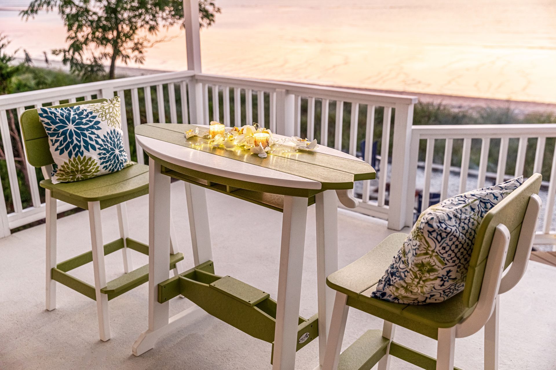 A table and chairs on a balcony with a view of the ocean.