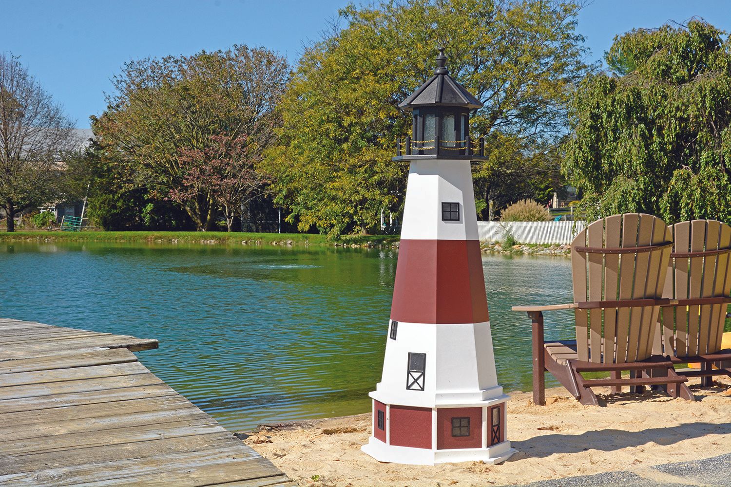 a red and white lighthouse sits on the beach near a lake