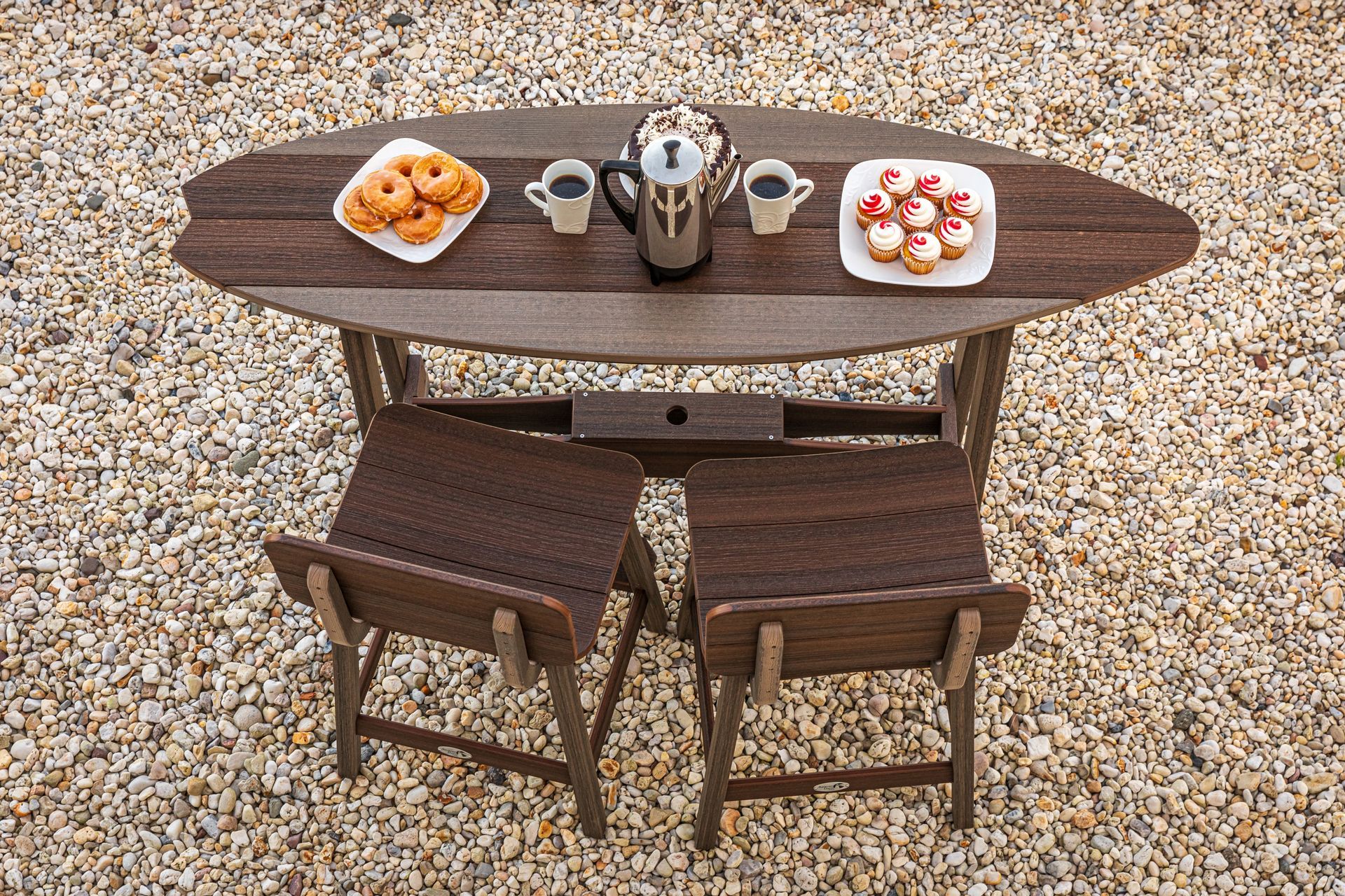 A wooden table with two chairs and two plates of food on it.