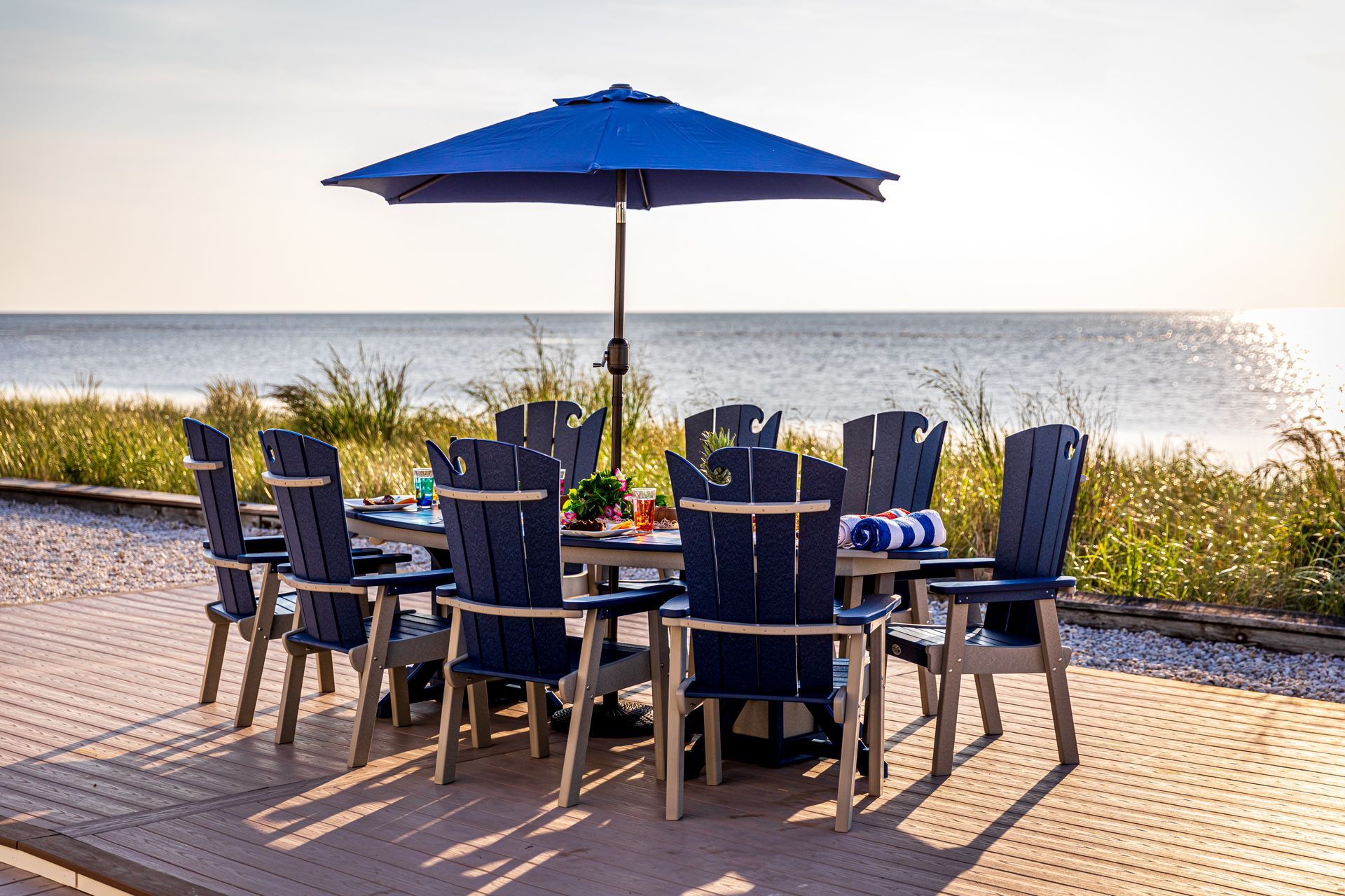 A table and chairs with an umbrella in front of the ocean.