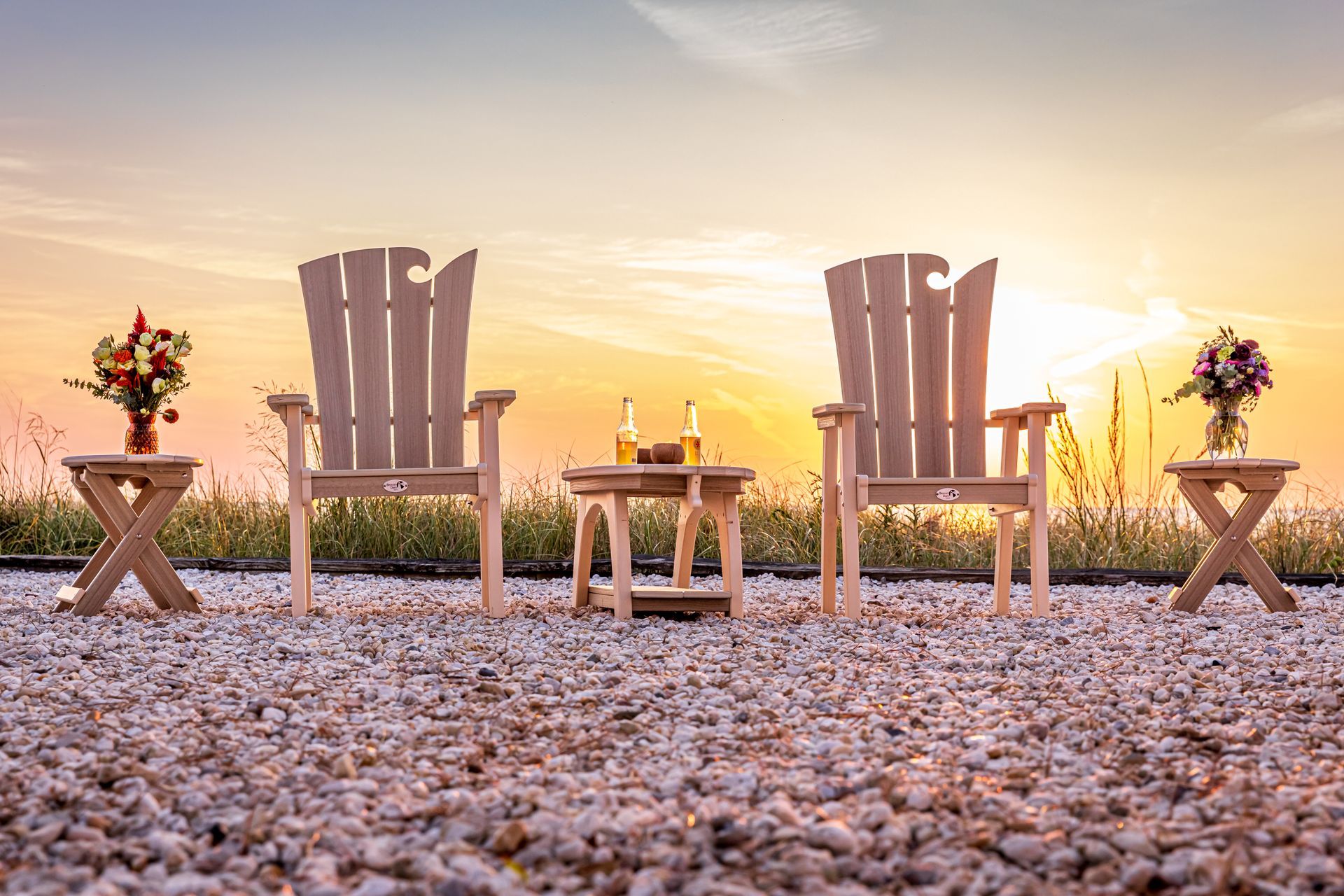 A row of wooden adirondack chairs sitting on top of a pile of gravel.